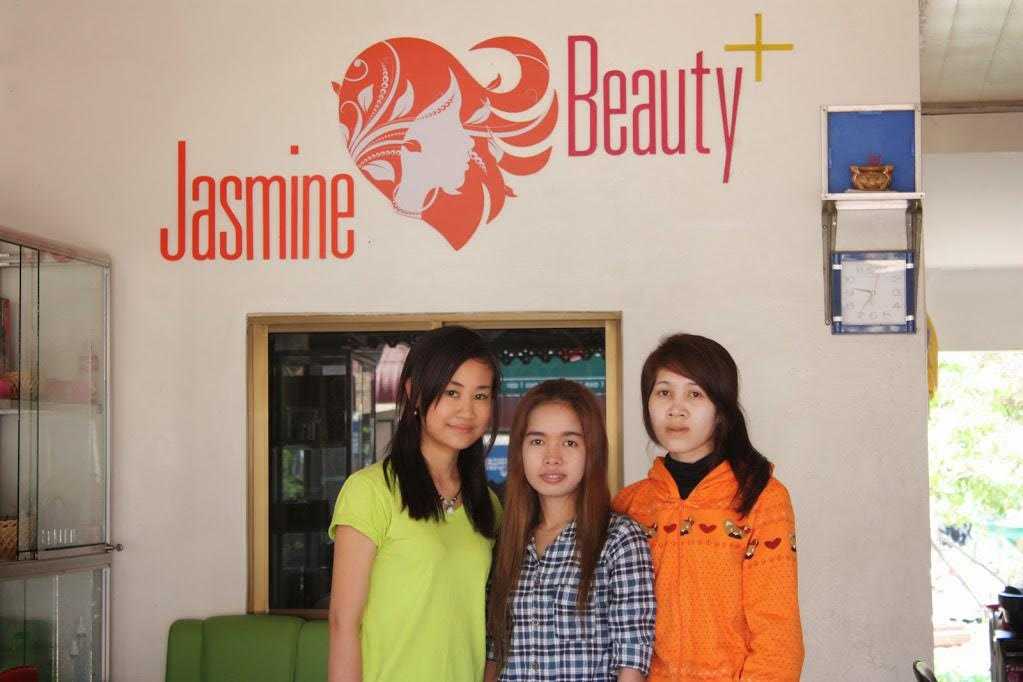 Jasmine stands with her workers in front of the sign for her salon